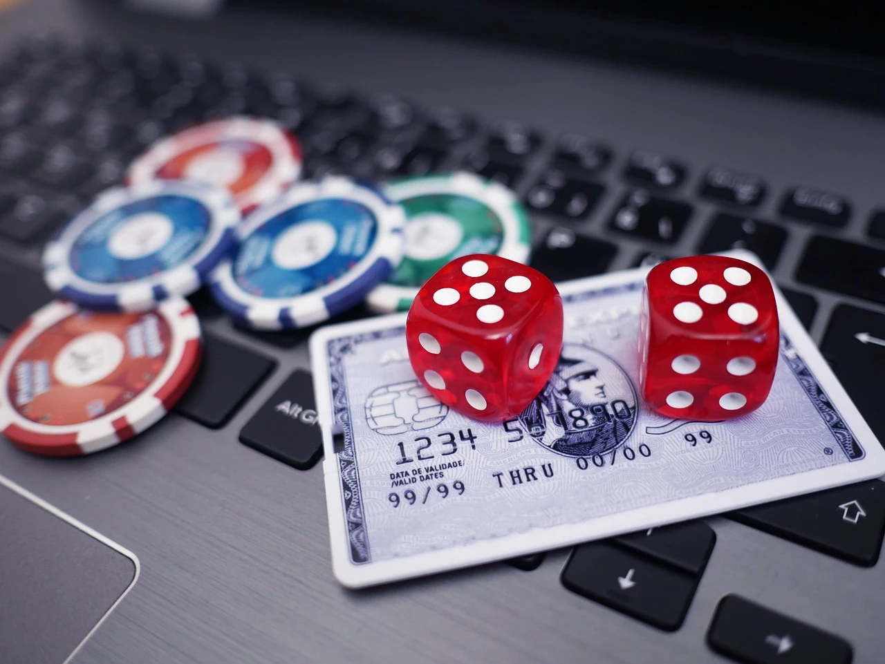 Casinochips, terninger og bankkort ved en bærbar PC